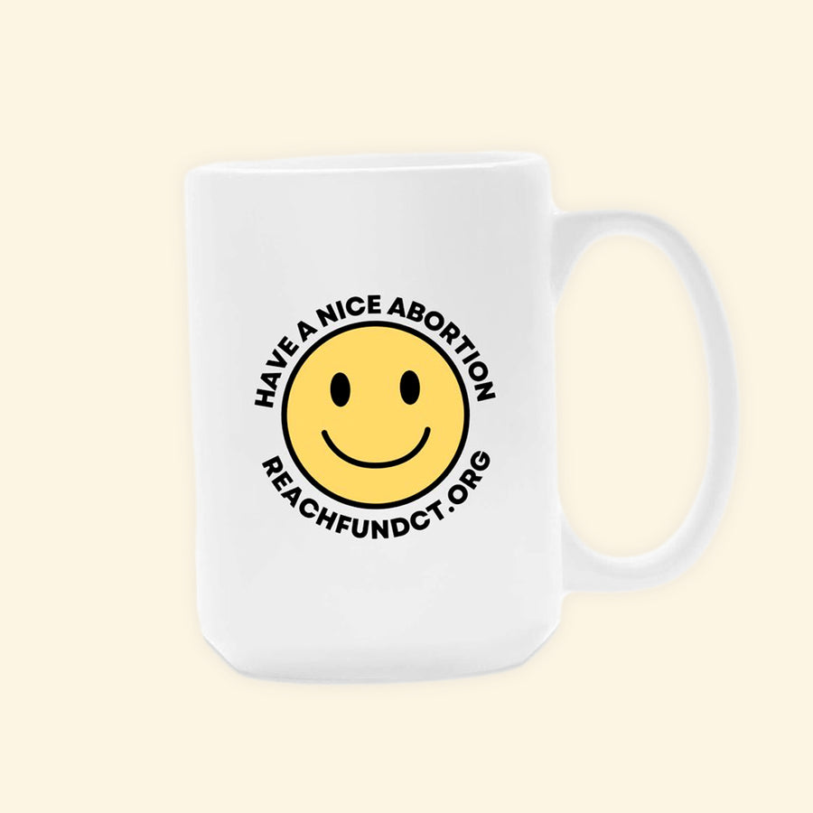 A white coffee mug featuring a yellow smile face, surrounded by the text "Have a nice abortion" and "Reach Fund C T dot org"