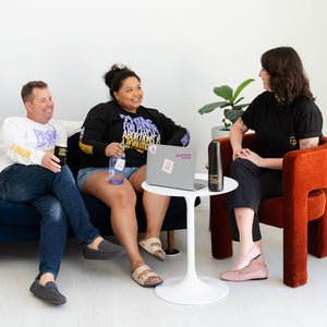 A group of three Jane's Due Process colleagues smile at each other while meeting around a laptop. They're decked out in abortion funds apparel.