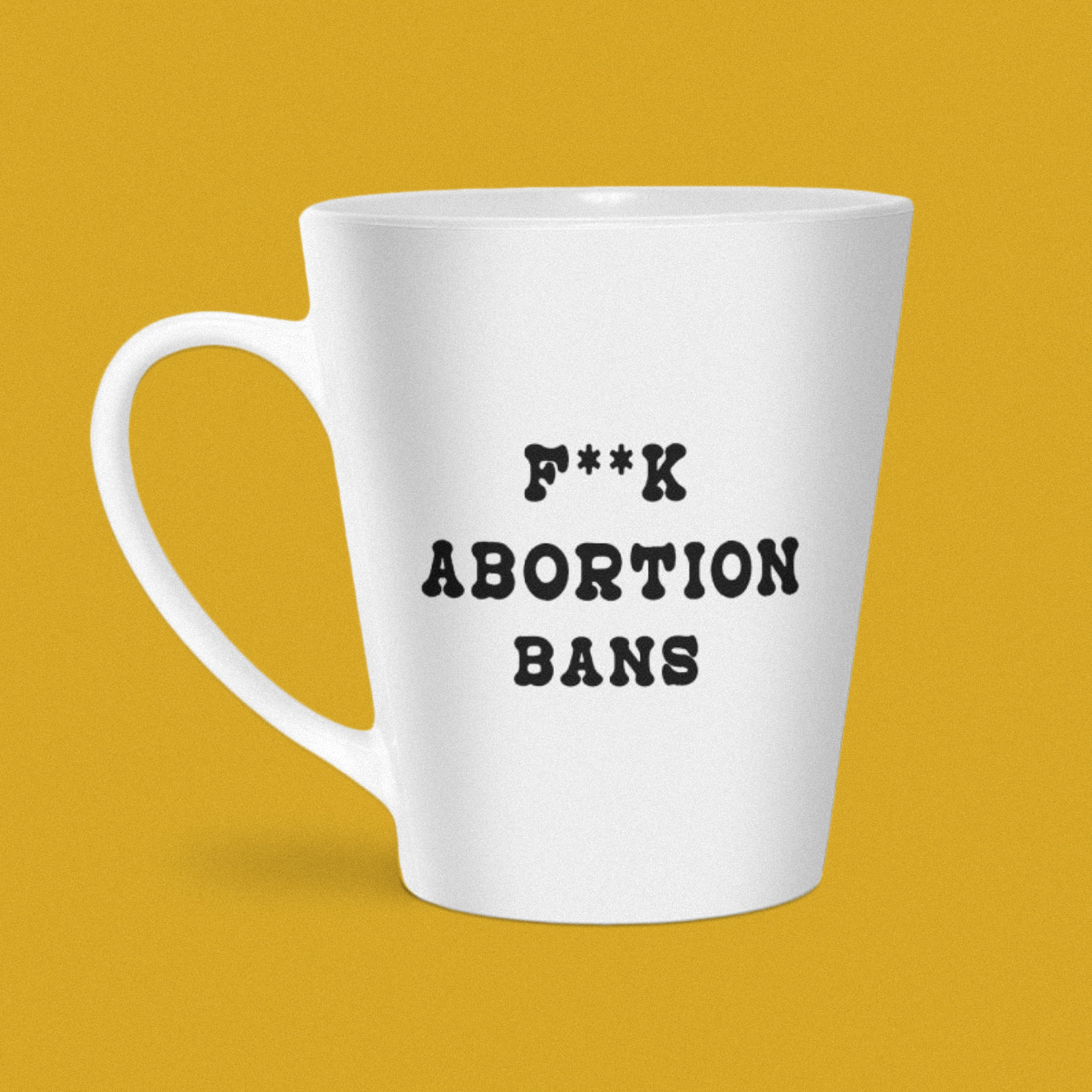 A white coffee mug reads F**K ABORTION BANS in bold black letters.